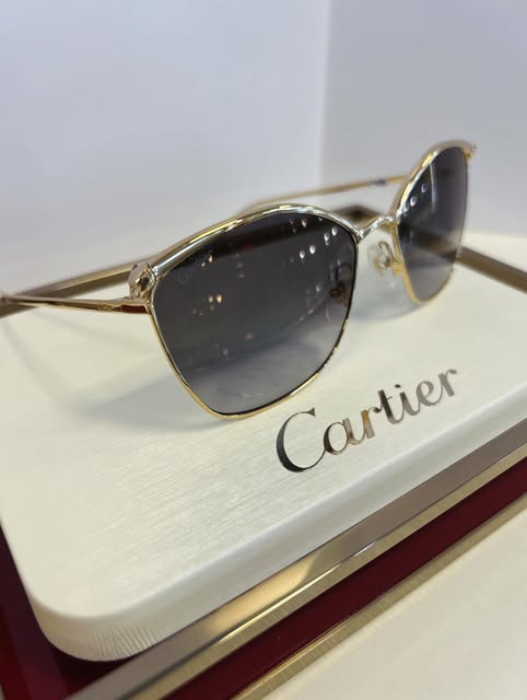 Gold metal Cartier sunglasses on a Cartier display stand